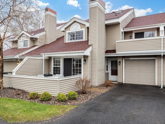 view of front of property featuring a shingled roof, a chimney, an attached garage, and aphalt driveway