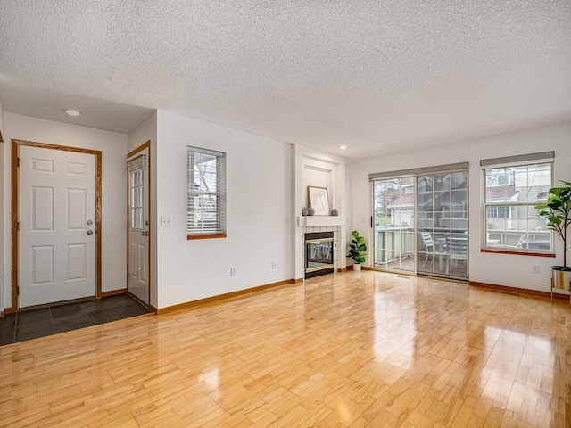 unfurnished living room with baseboards, a textured ceiling, wood finished floors, and a fireplace