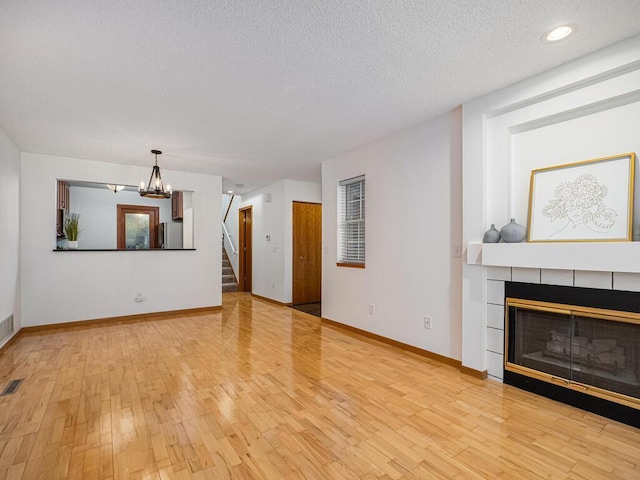 unfurnished living room featuring stairs, baseboards, a notable chandelier, and wood finished floors