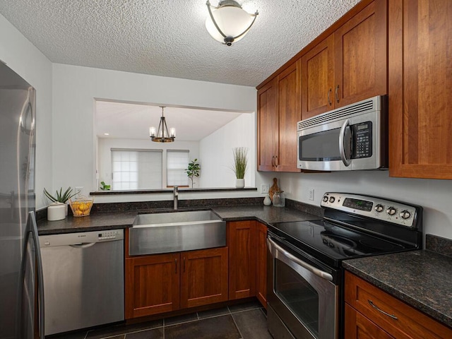 kitchen featuring brown cabinets, a chandelier, appliances with stainless steel finishes, and a sink