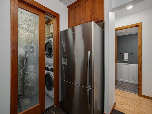 clothes washing area with laundry area, visible vents, dark wood-style flooring, a wainscoted wall, and stacked washer / drying machine
