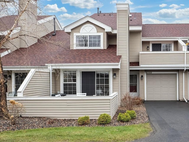 view of front of property featuring an attached garage, a shingled roof, aphalt driveway, and a chimney