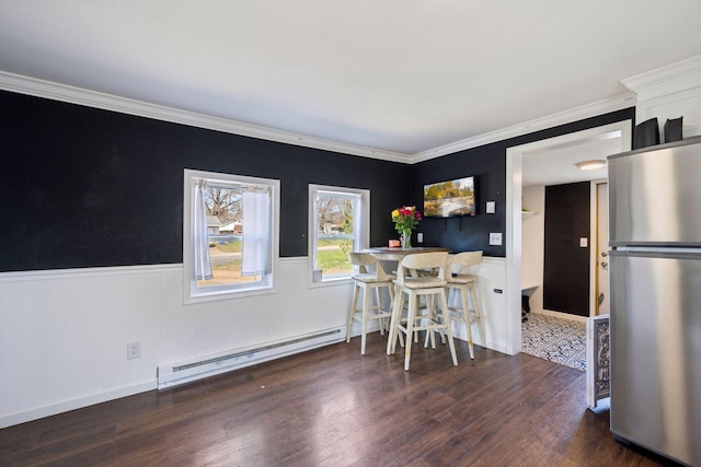 538 Jackson Ave NW, Elk River, MN 55330 - dining space featuring wainscoting, baseboard heating, wood finished floors, and crown molding