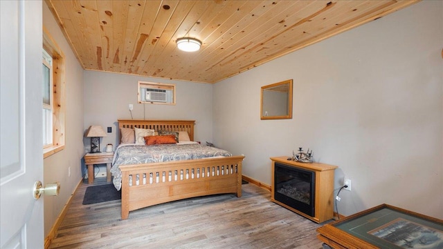bedroom featuring wooden ceiling, baseboards, wood finished floors, and a wall unit AC