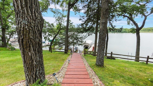 exterior space featuring a lawn, boat lift, a water view, and a dock