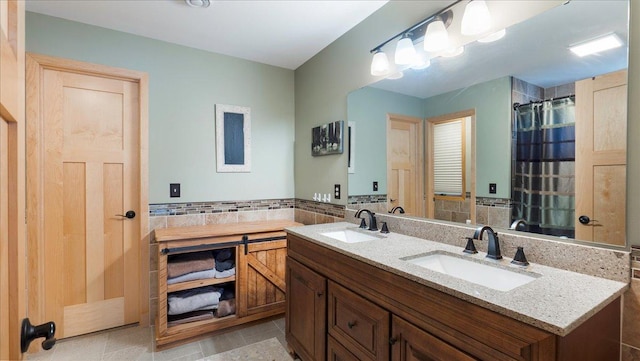 bathroom featuring curtained shower, double vanity, tile walls, and a sink