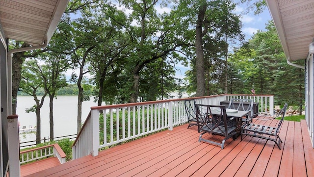 deck with outdoor dining space and a water view