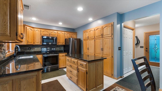 kitchen with stainless steel appliances, a center island, a sink, visible vents, and decorative backsplash