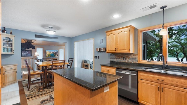 kitchen featuring a sink, decorative backsplash, dishwasher, visible vents, and a kitchen island