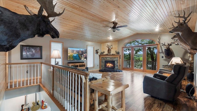 living room featuring vaulted ceiling, wood finished floors, a ceiling fan, wooden ceiling, and a fireplace