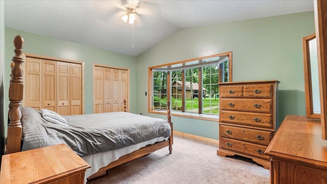 bedroom featuring light carpet, baseboards, lofted ceiling, a ceiling fan, and multiple closets