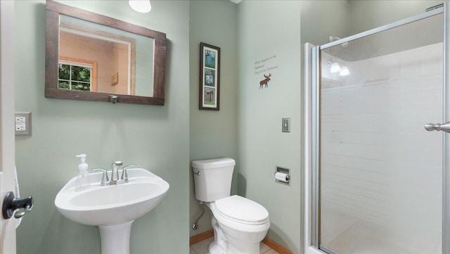 bathroom featuring baseboards, toilet, a stall shower, and a sink