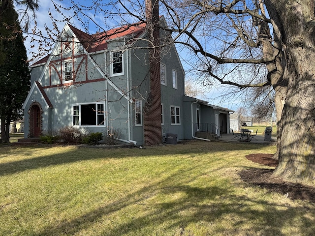201 2nd St W, Chokio, MN 56221 - rear view of house with a chimney, a yard, cooling unit, and stucco siding