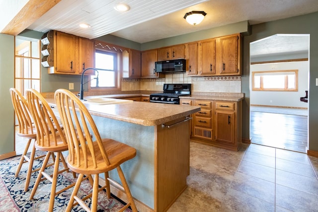 kitchen with black appliances, a peninsula, brown cabinets, baseboards, and recessed lighting