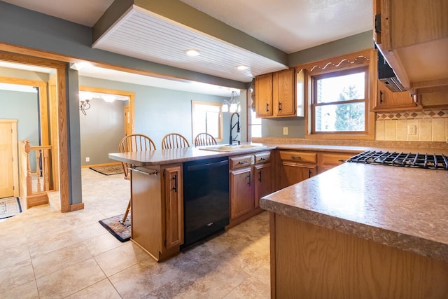 kitchen with black dishwasher, a sink, a peninsula, brown cabinetry, and decorative backsplash