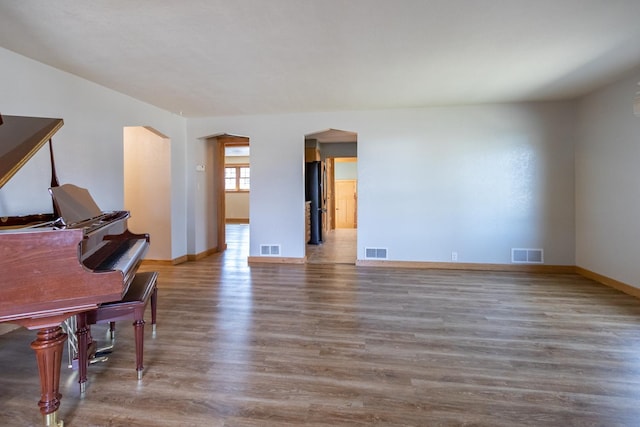 living room featuring wood finished floors, arched walkways, and baseboards