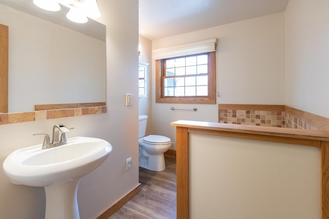 bathroom with toilet, wood finished floors, a sink, and backsplash