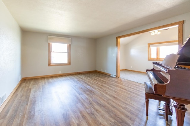 unfurnished living room featuring plenty of natural light, light wood-style floors, and baseboards