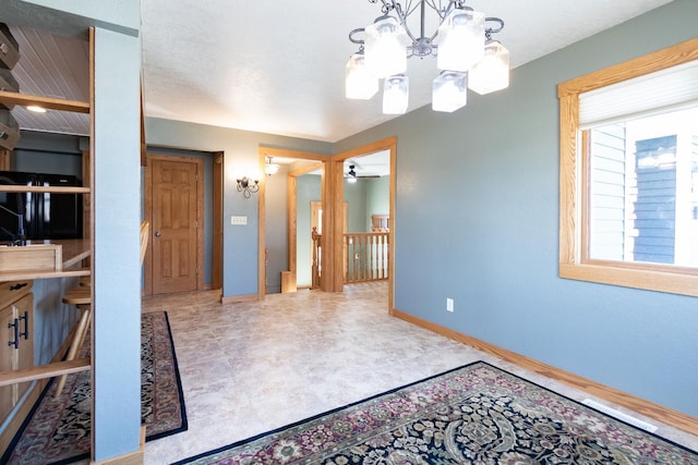 unfurnished dining area featuring a chandelier, baseboards, and a ceiling fan