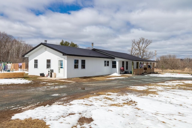 snow covered back of property with a wooden deck