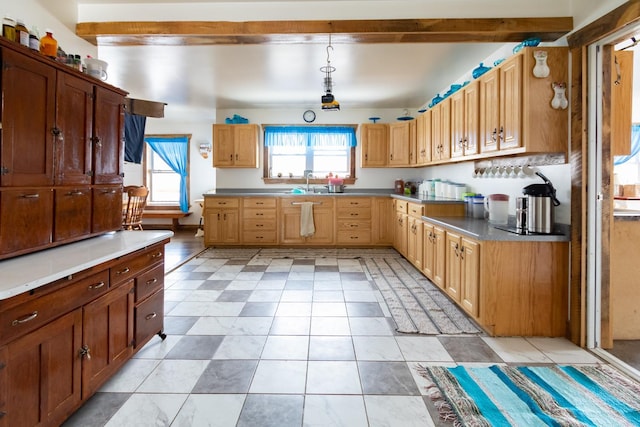 kitchen featuring a sink, hanging light fixtures, light countertops, and plenty of natural light