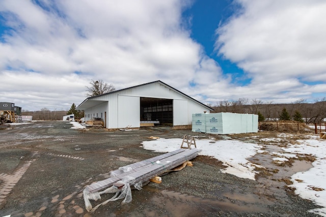 snow covered structure featuring an outdoor structure, fence, and an outbuilding