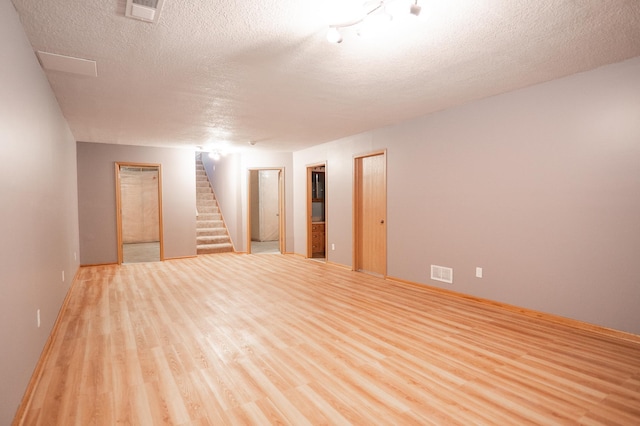 15174 Cates Lake Dr, Savage, MN 55372 - empty room with light wood-type flooring, visible vents, a textured ceiling, and stairs
