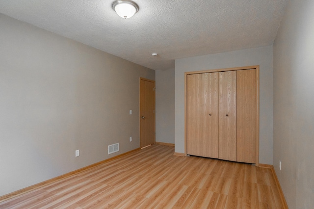 15174 Cates Lake Dr, Savage, MN 55372 - unfurnished bedroom featuring visible vents, light wood-type flooring, a closet, baseboards, and a textured ceiling