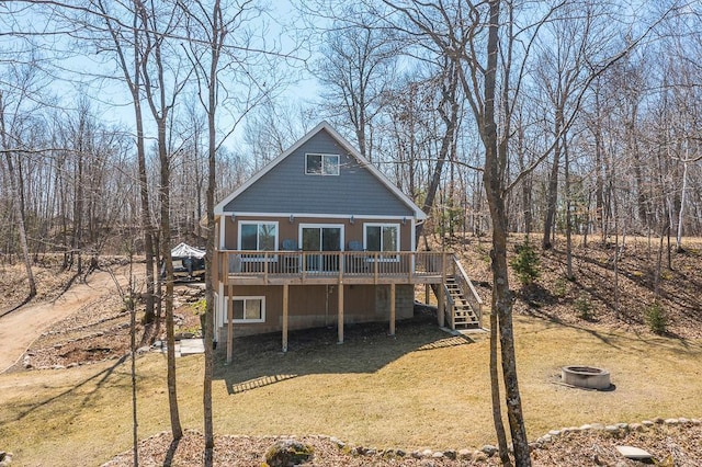 back of house with an outdoor fire pit, a deck, stairway, and a yard