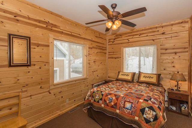 carpeted bedroom featuring wood walls and ceiling fan