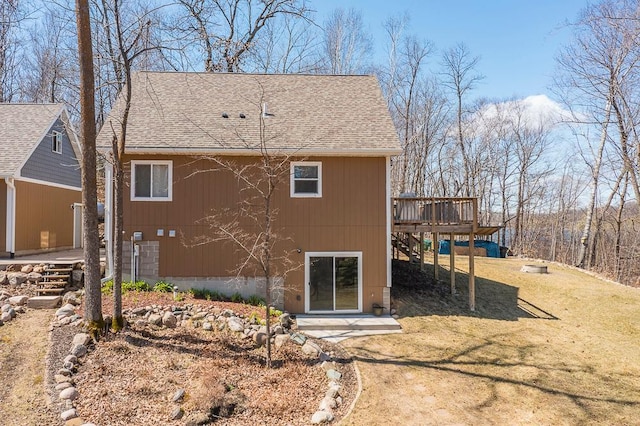 back of property featuring stairs, a wooden deck, roof with shingles, and a lawn