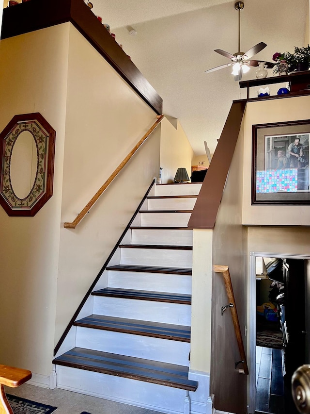 stairway featuring ceiling fan, high vaulted ceiling, and baseboards