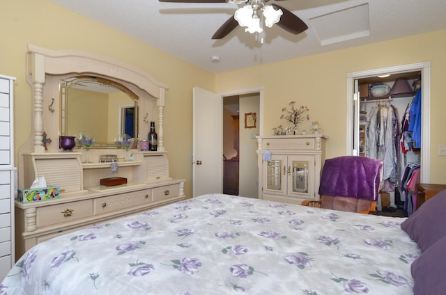 bedroom with a walk in closet, ceiling fan, a closet, and attic access