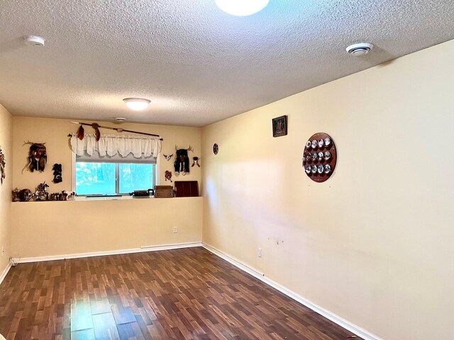 unfurnished room featuring wood finished floors, a textured ceiling, baseboards, and a smoke detector