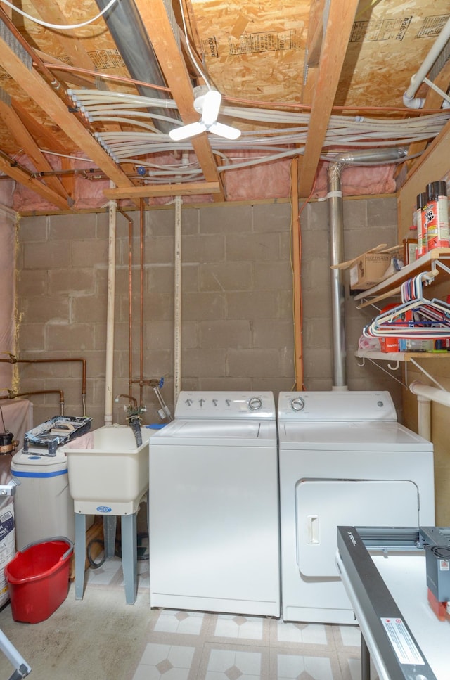 clothes washing area with independent washer and dryer, light floors, and concrete block wall