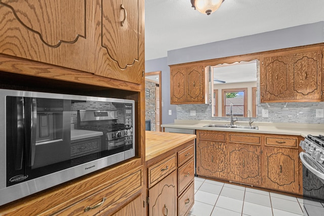 4418 Chowen Ave N, Robbinsdale, MN 55422 - kitchen with a sink, appliances with stainless steel finishes, brown cabinets, light tile patterned floors, and backsplash