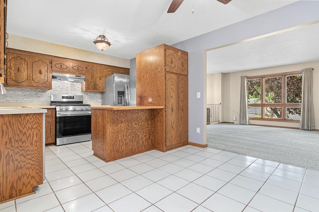 4418 Chowen Ave N, Robbinsdale, MN 55422 - kitchen with stainless steel appliances, under cabinet range hood, brown cabinetry, and light countertops