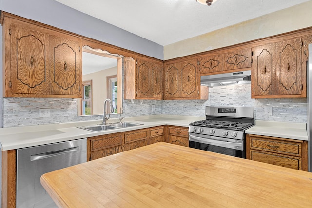 4418 Chowen Ave N, Robbinsdale, MN 55422 - kitchen with under cabinet range hood, appliances with stainless steel finishes, brown cabinets, and light countertops