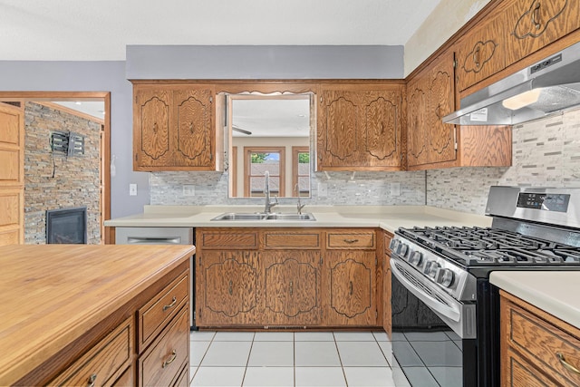 4418 Chowen Ave N, Robbinsdale, MN 55422 - kitchen featuring stainless steel gas stove, under cabinet range hood, brown cabinetry, and tasteful backsplash
