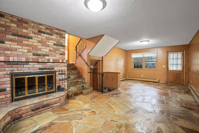 unfurnished living room with a baseboard heating unit, stone flooring, a textured ceiling, and stairs