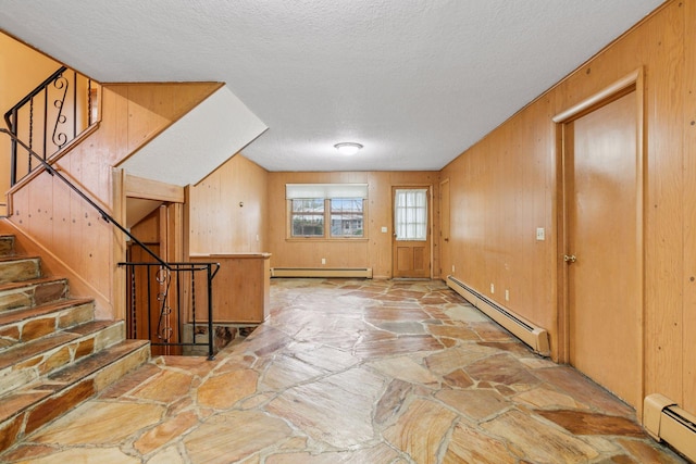 interior space with a baseboard radiator, a textured ceiling, stone flooring, and baseboard heating
