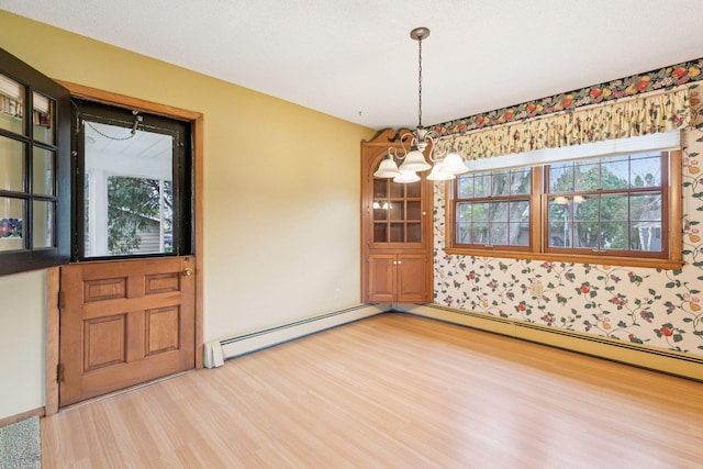 unfurnished dining area with light wood-style floors, a baseboard radiator, wallpapered walls, and a chandelier