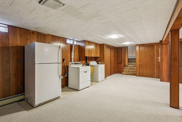 basement with freestanding refrigerator, wood walls, light carpet, washer and clothes dryer, and a baseboard heating unit