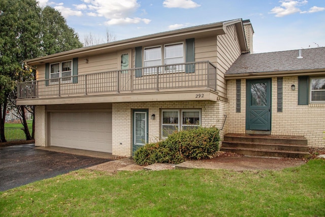tri-level home featuring driveway, a garage, brick siding, a balcony, and a front lawn
