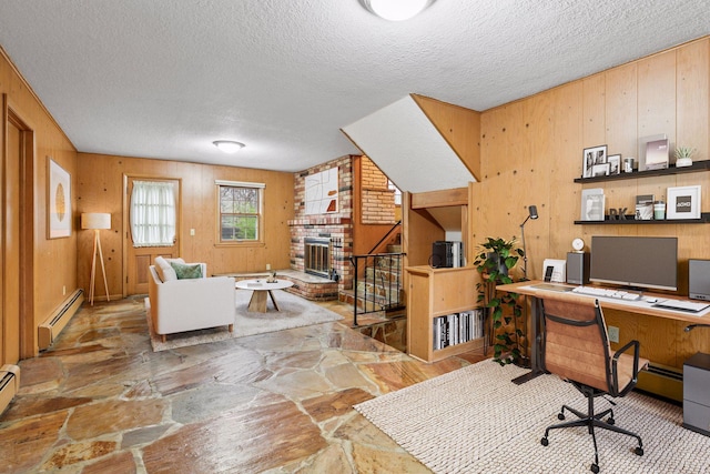 office space with a baseboard radiator, a brick fireplace, stone flooring, and a textured ceiling