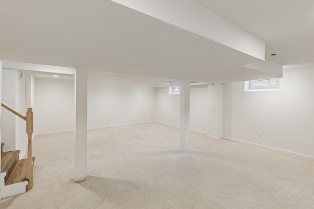 basement with light carpet, baseboards, and stairway