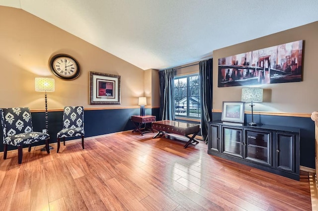 living area with vaulted ceiling and wood finished floors