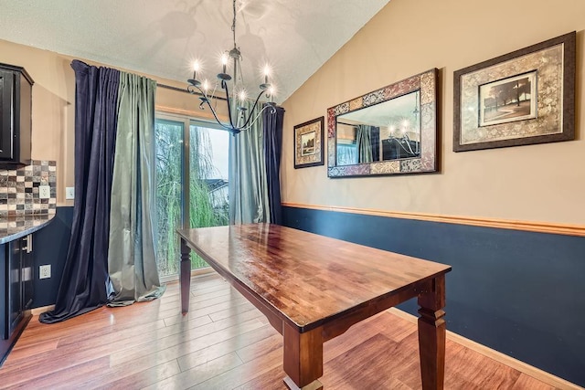 dining area featuring vaulted ceiling, wood finished floors, and a chandelier
