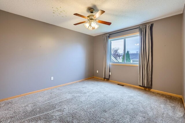 empty room featuring visible vents, a ceiling fan, baseboards, a textured ceiling, and carpet flooring