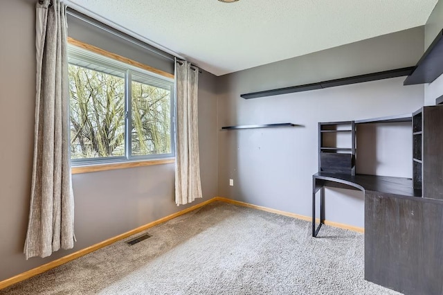 unfurnished office featuring a textured ceiling, carpet, visible vents, and baseboards